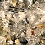 Sabbia di disfacimento di una roccia metamorfica a silicati raccolta in un torrente di montagna . Cristallini di quarzo, frammenti di quarzo ialino, sopra sono visti al polarizzatore.